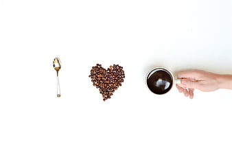 Flat lay of coffee beans heart shape and cup on white