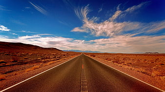 Endless desert highway stretching to horizon under blue sky