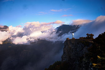 Man Standing on Cliff Edge Overlooking Sea of Clouds