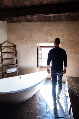 Man Walking Away in Rustic Bathroom Interior