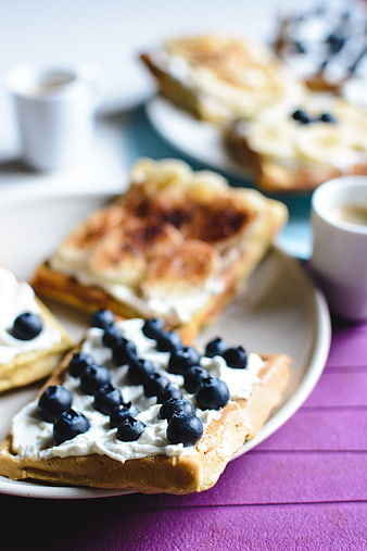 Waffles with blueberries and bananas on a purple table