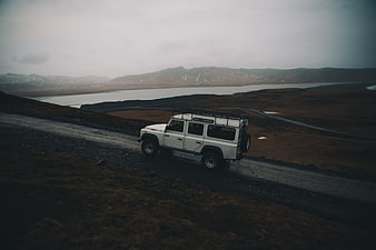White SUV on Gravel Road in Moody Highland Landscape