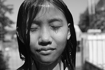 Close-up portrait of a crying girl with wet hair in black and white