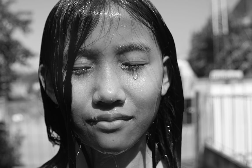 Close-up portrait of a crying girl with wet hair in black and white