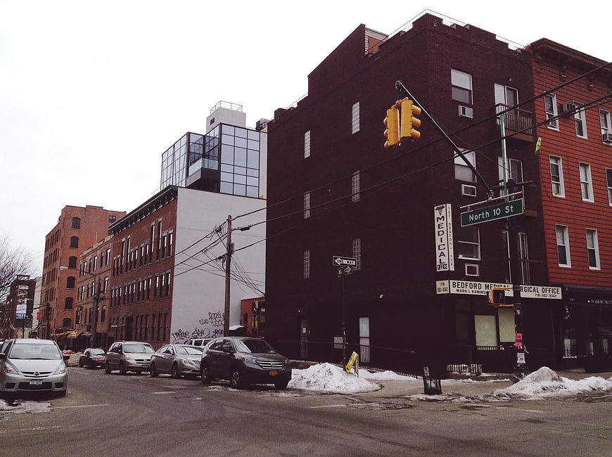 Urban street corner in Brooklyn with snow piles and brick buildings