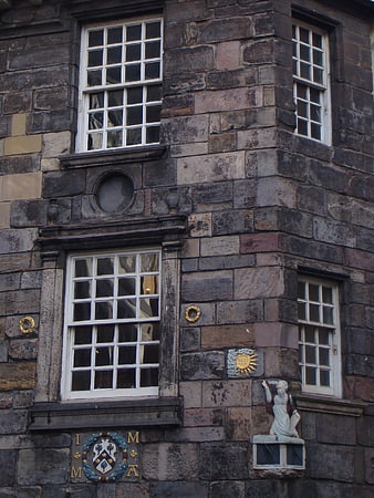 Historic stone building facade with white windows and crest