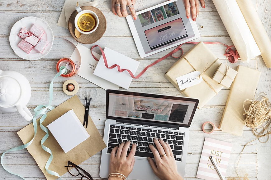 Flat lay of online shopping workspace with laptop, tablet, and gifts