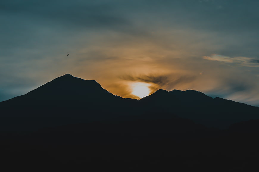 Silhouette of mountain peaks against dramatic sunset sky