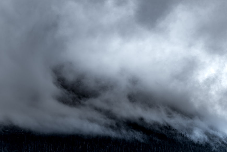 Dramatic Dark Storm Clouds Rolling Over Forested Mountain Ridge