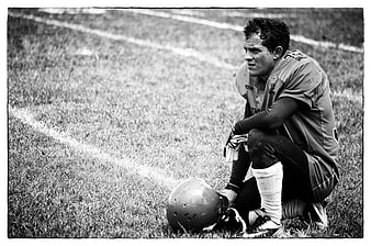Tired American Football Player Kneeling on Field in Black and White