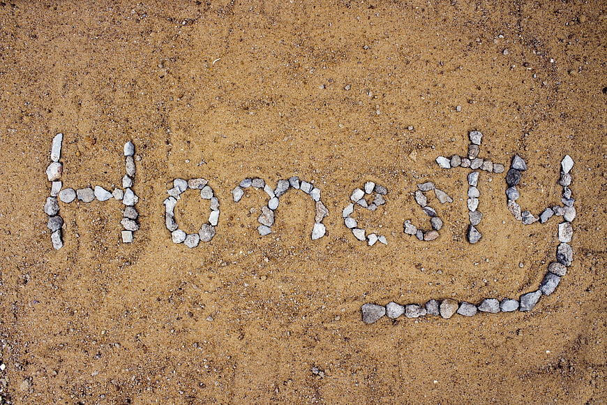 Honesty word spelled with small stones on sandy ground