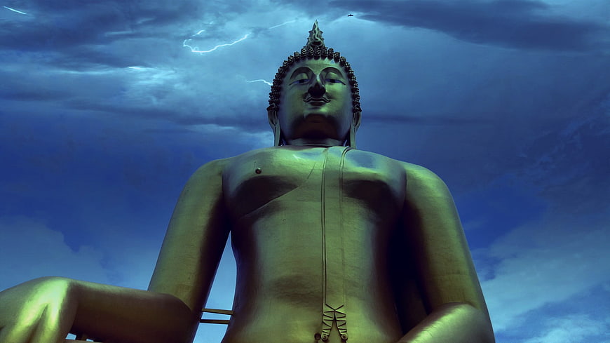 Golden Buddha Statue Against Dramatic Stormy Sky