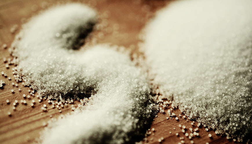 Close-up of white salt grains on a wooden surface