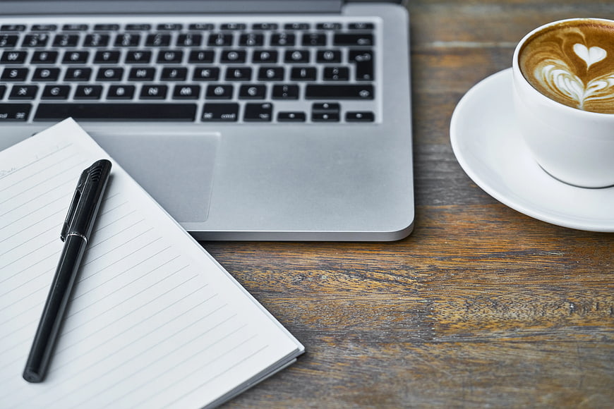 Laptop, Coffee, and Notebook on Wooden Desk