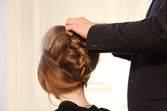 Stylist arranging elegant hair updo on female model during fashion demonstration