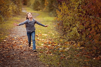 Happy Girl Running on Autumn Path with Leaves