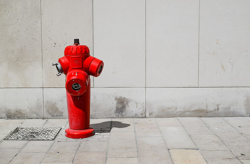 Red fire hydrant on city sidewalk against concrete wall