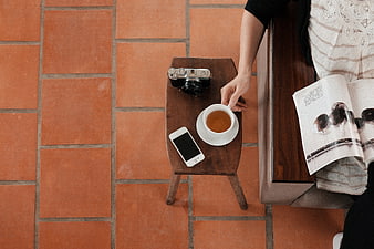 Top view of coffee, camera, and smartphone on wooden stool