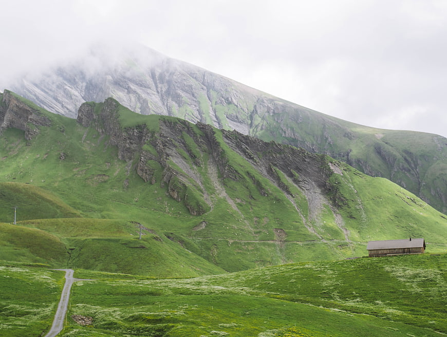 Lush Green Mountain Landscape with Wooden Cabin and Winding Road