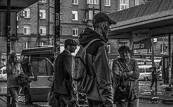 Black and white street photography of people waiting at a bus stop in the rain