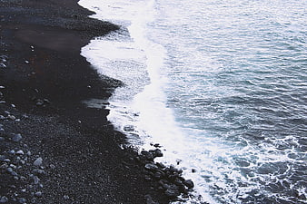 Aerial view of black sand beach with crashing ocean waves