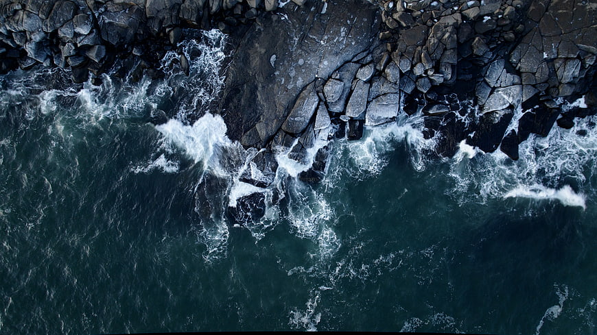 Aerial View of Waves Crashing on Rocky Coastline
