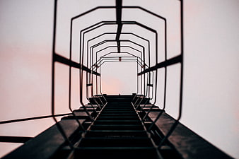 Low angle view of metal tower stairs against sunset sky
