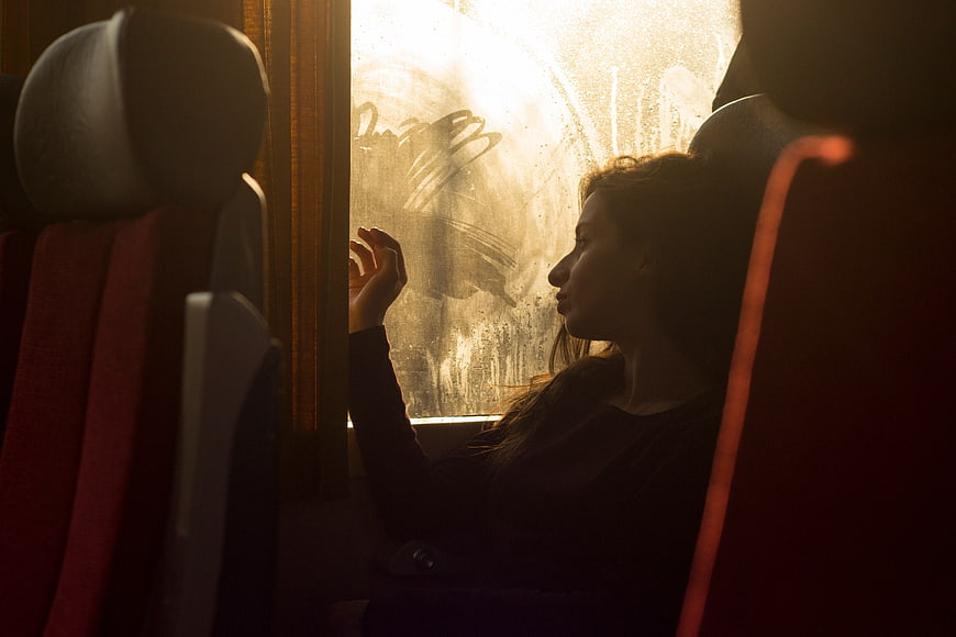 Woman looking out of foggy train window in silhouette