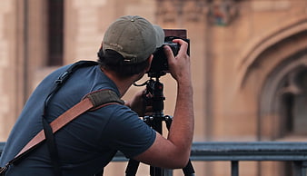 Male photographer using camera on tripod in front of historic architecture