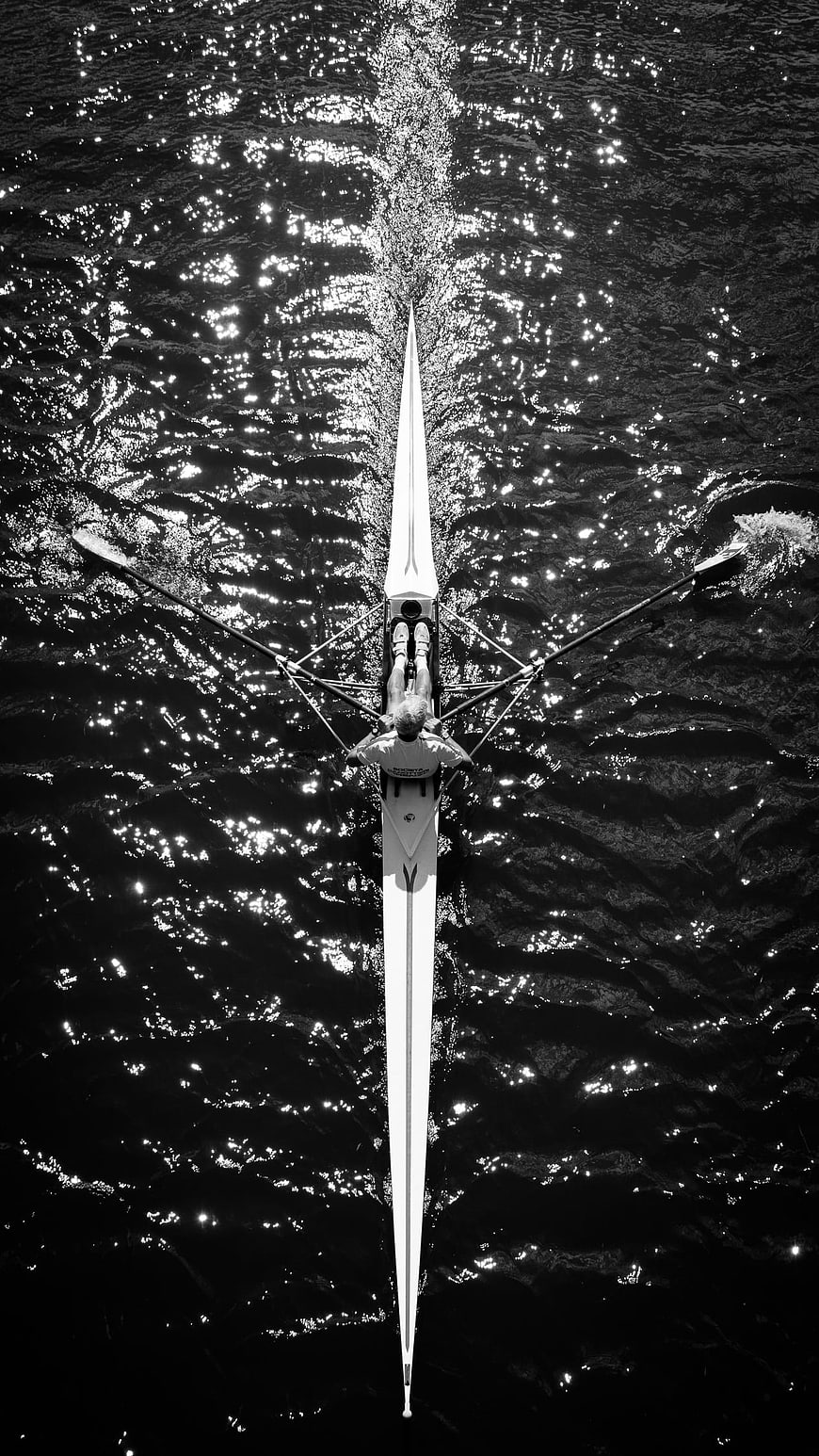 Aerial black and white view of a rower on sparkling water