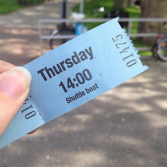 Hand holding blue shuttle boat ticket outdoors