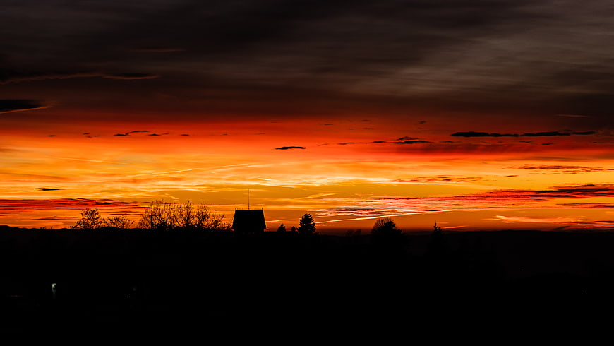 Dramatic fiery sunset over silhouetted rural landscape