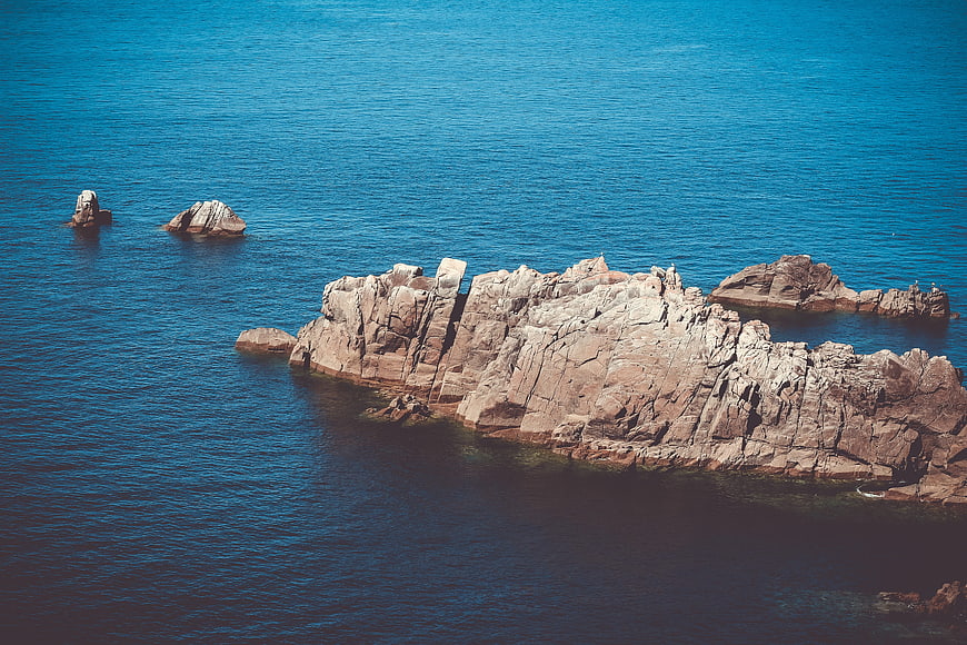 Aerial View of Rocky Outcrop in Blue Ocean Water