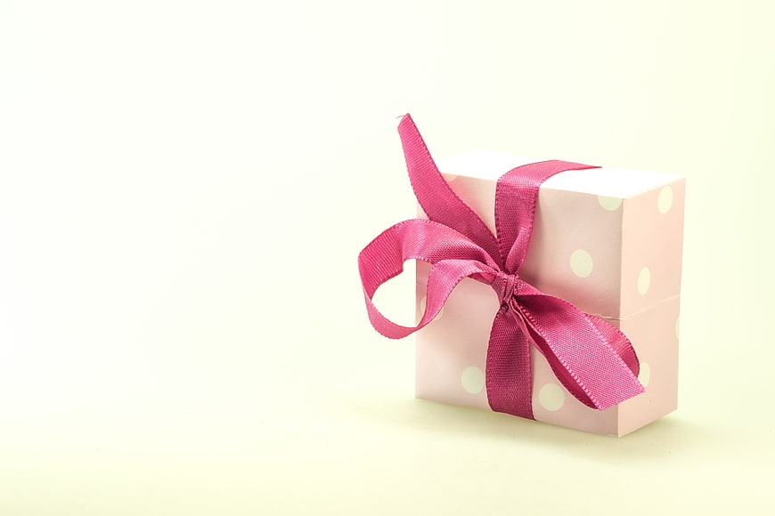 Pink polka dot gift box with magenta ribbon on white background