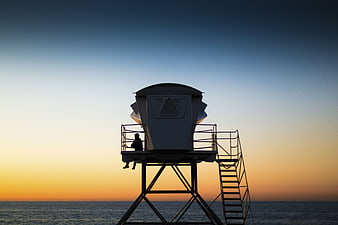 Silhouette of Lifeguard Tower at Sunset Over Ocean