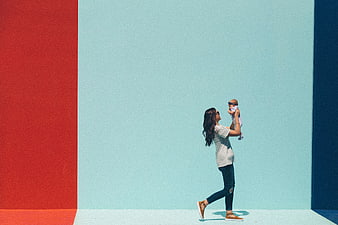 Mother holding baby against colorful geometric wall