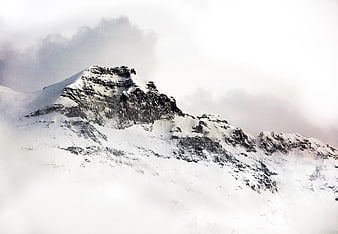 Snowy Mountain Peak Emerging Through Thick Clouds