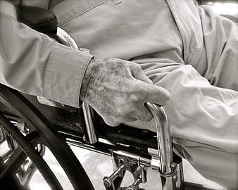 Close-up of elderly hand gripping wheelchair handle