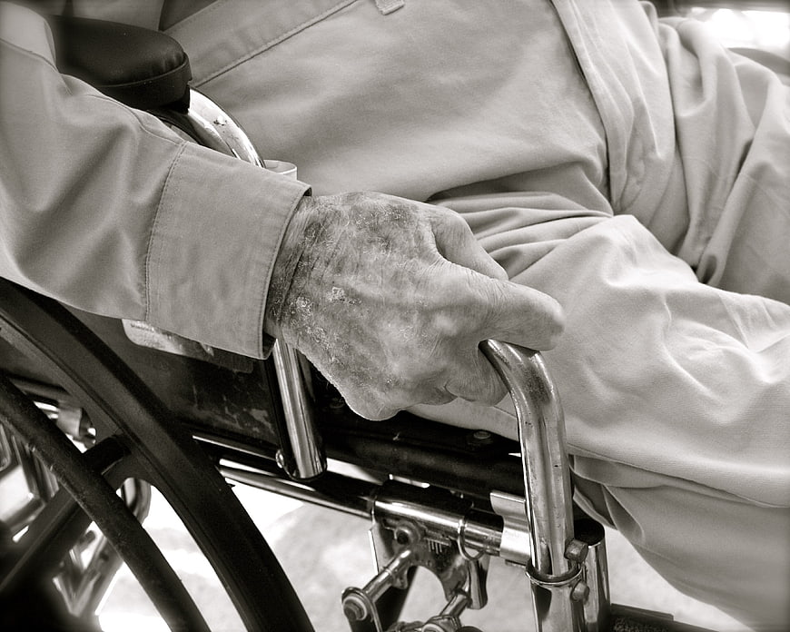 Close-up of elderly hand gripping wheelchair handle