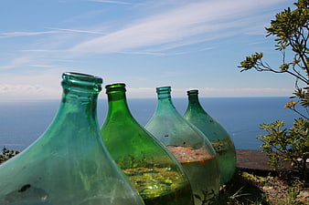 Green glass bottles overlooking the blue ocean horizon