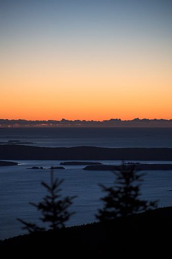 Serene Sunset Over Ocean Islands with Silhouetted Trees