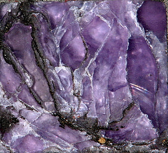 Close-up of purple amethyst crystal texture with fractures