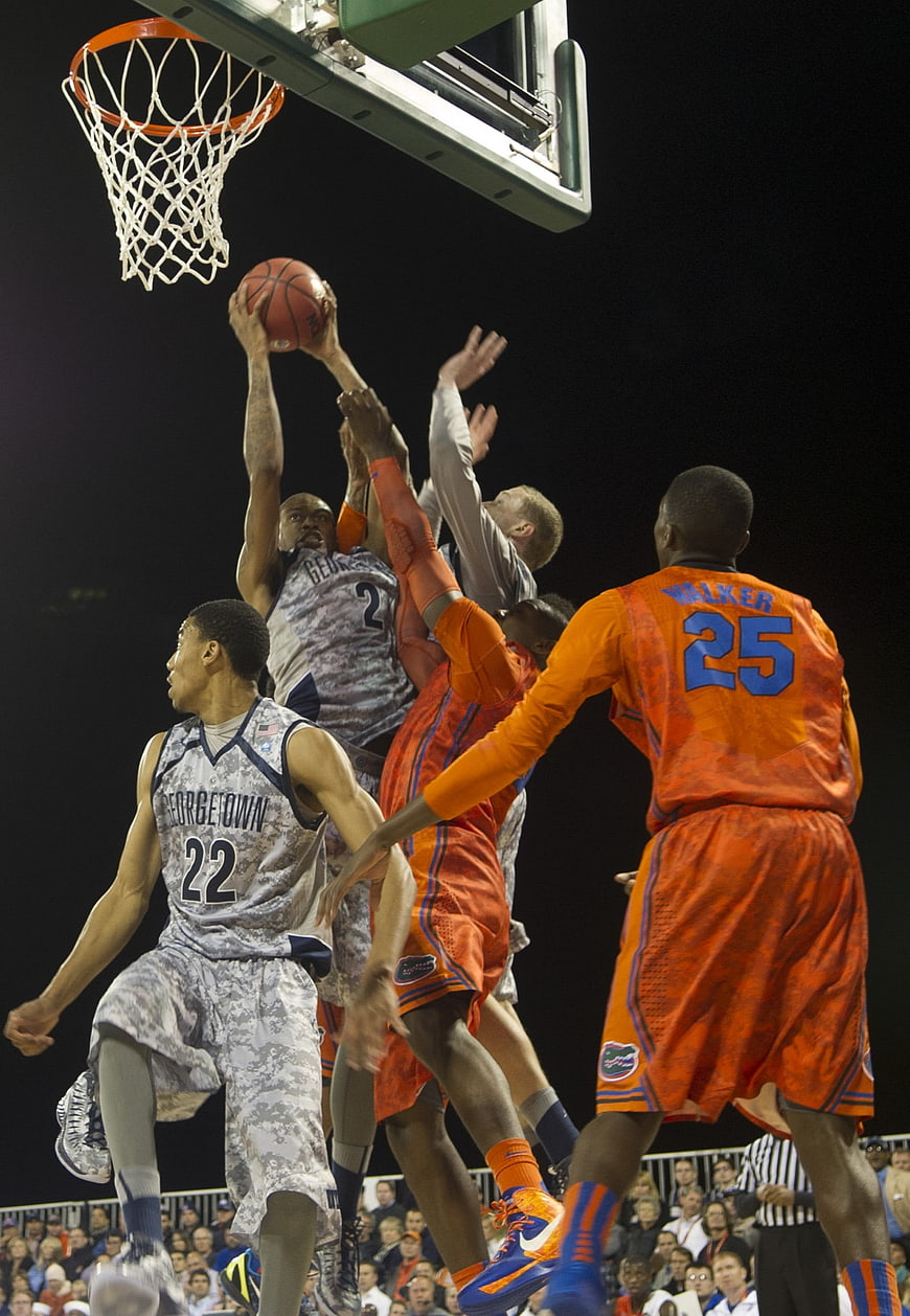 College basketball players jumping for a layup at night