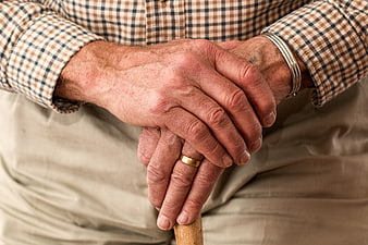 Close-up of elderly man's hands holding a walking stick
