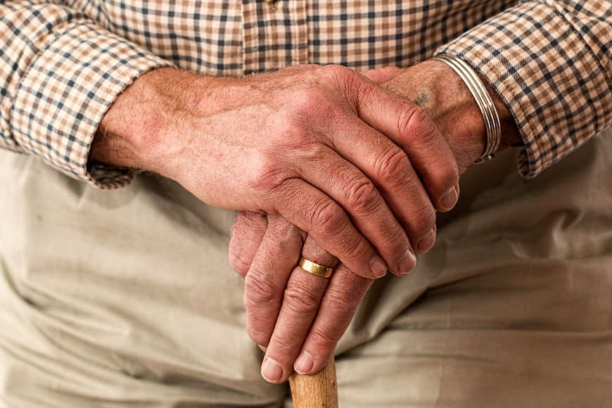 Close-up of elderly man's hands holding a walking stick