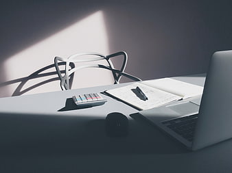 Minimalist workspace with laptop, notebook, and calculator in sunlight