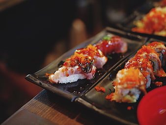 Gourmet sushi rolls with spicy sauce on black plates