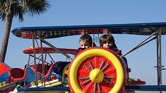 Two children riding a colorful airplane carnival ride