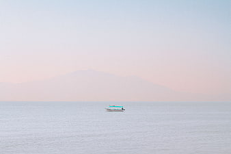 Minimalist boat on calm sea with distant mountain silhouette