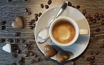Top view of espresso with heart chocolates and sugar on wood